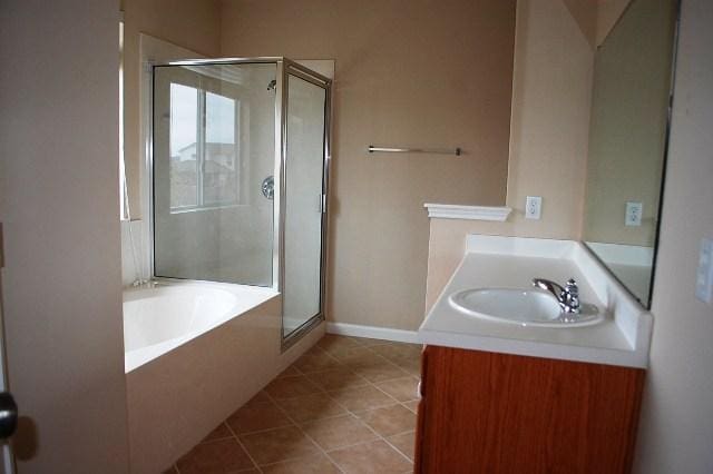 205 E Mitchell Dr, Hutto, TX 78634 - bathroom featuring a shower stall, vanity, a bath, and tile patterned floors