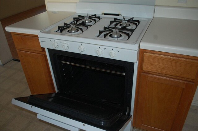 205 E Mitchell Dr, Hutto, TX 78634 - kitchen view of white gas stove, brown cabinetry, light countertops, and light floors