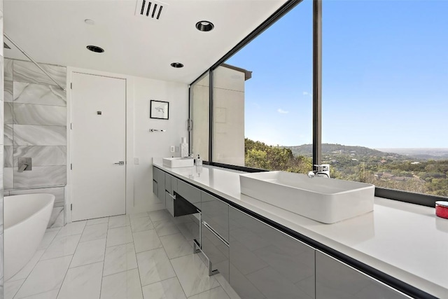 1501 Ridgecrest Dr, Austin, TX 78746 - bathroom featuring a soaking tub, double vanity, and marble finish flooring