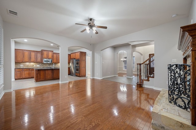 1116 Castle Path, Round Rock, TX 78681 - unfurnished living room with a ceiling fan, light wood-style floors, stairway, and arched walkways