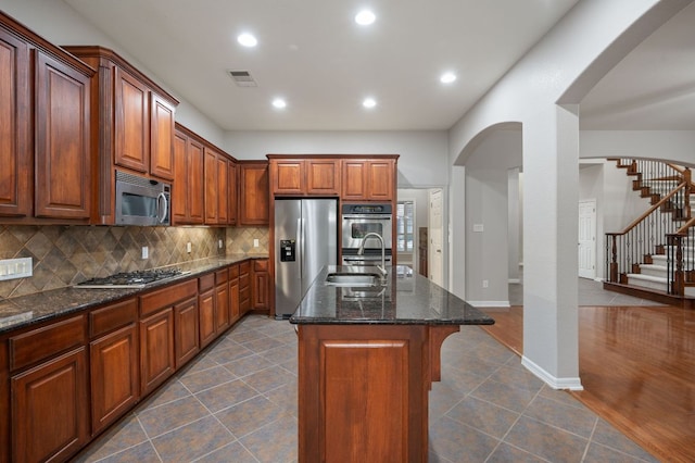 1116 Castle Path, Round Rock, TX 78681 - kitchen with stainless steel appliances, arched walkways, backsplash, dark tile patterned flooring, and dark stone counters