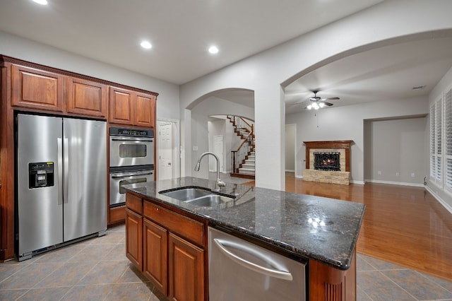 1116 Castle Path, Round Rock, TX 78681 - kitchen with stainless steel appliances, ceiling fan, a fireplace, dark stone counters, and an island with sink