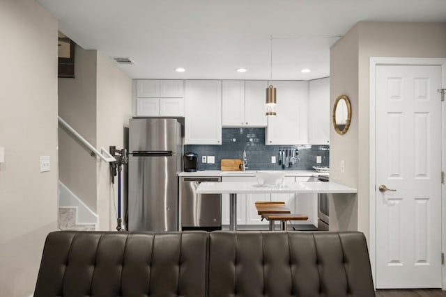 935 La Posada Dr Unit 148, Austin, TX 78752 - kitchen featuring stainless steel appliances, light countertops, white cabinetry, tasteful backsplash, and pendant lighting