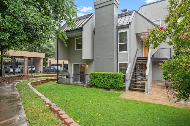 935 La Posada Dr Unit 148, Austin, TX 78752 - rear view of property featuring a standing seam roof, stucco siding, a metal roof, stairway, and a chimney