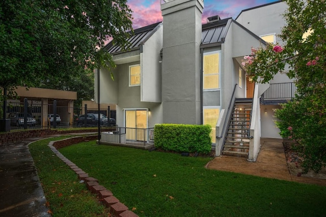 935 La Posada Dr Unit 148, Austin, TX 78752 - back of property with a standing seam roof, stairway, stucco siding, a metal roof, and a chimney