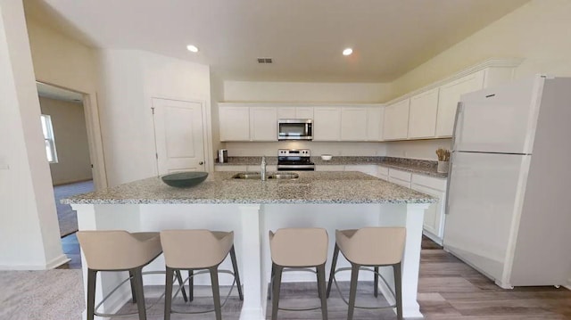 315 Pond Dr, Maxwell, TX 78656 - kitchen with stainless steel appliances, white cabinets, a breakfast bar, a center island with sink, and recessed lighting