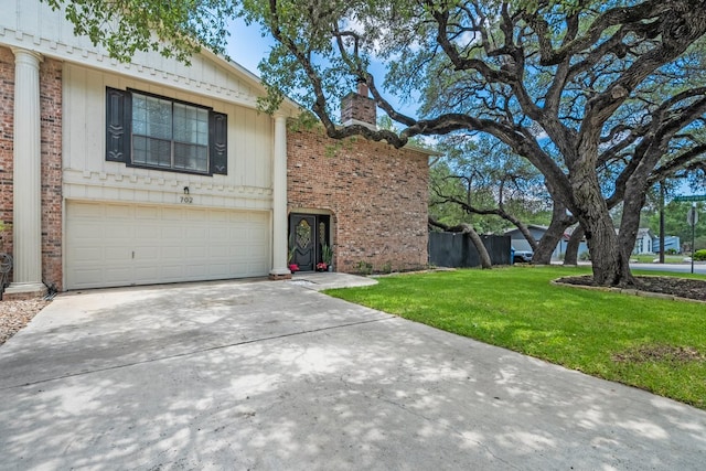 702 California Blvd Unit 702, New Braunfels, TX 78130 - view of front of property with concrete driveway, a front yard, an attached garage, a chimney, and brick siding