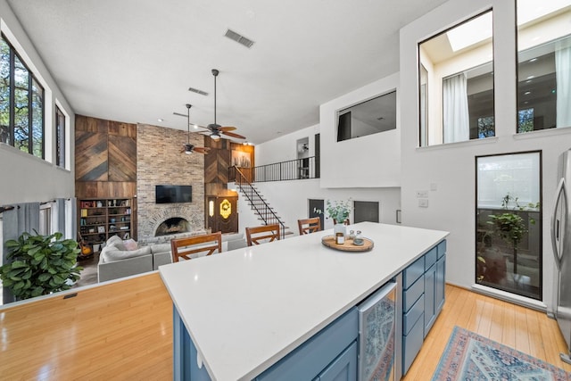702 California Blvd Unit 702, New Braunfels, TX 78130 - kitchen with blue cabinets, a fireplace, wine cooler, a ceiling fan, and light wood-style floors