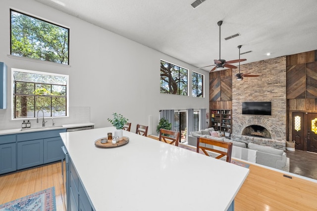 702 California Blvd Unit 702, New Braunfels, TX 78130 - kitchen featuring blue cabinetry, light countertops, a center island, a brick fireplace, and a textured ceiling