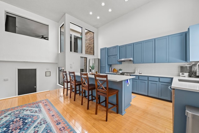 702 California Blvd Unit 702, New Braunfels, TX 78130 - kitchen with blue cabinetry, a high ceiling, a breakfast bar, light countertops, and backsplash