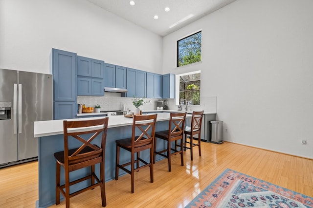 702 California Blvd Unit 702, New Braunfels, TX 78130 - kitchen featuring stainless steel fridge with ice dispenser, a high ceiling, blue cabinetry, a breakfast bar area, and light countertops