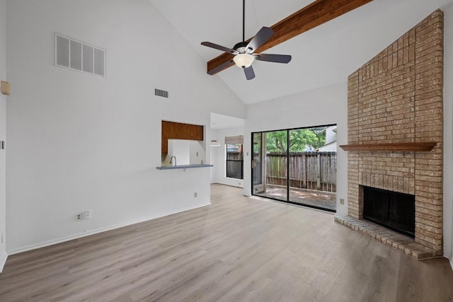3801 Menchaca Rd Unit 6, Austin, TX 78704 - unfurnished living room featuring high vaulted ceiling, wood finished floors, ceiling fan, a brick fireplace, and beamed ceiling