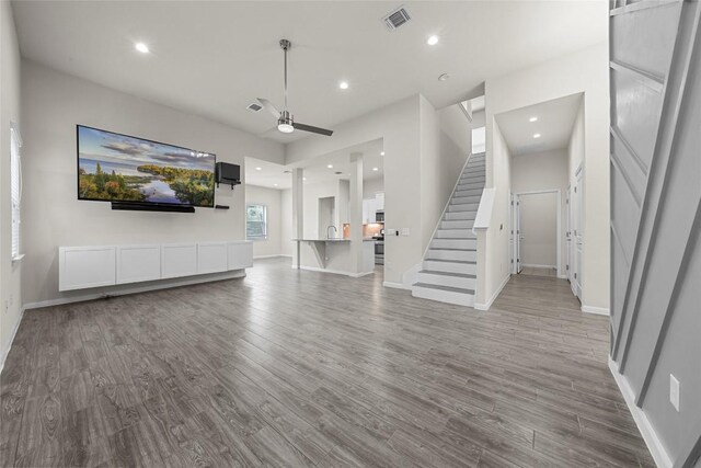 7808 Glover Dr, Austin, TX 78744 - unfurnished living room featuring wood finished floors, stairway, ceiling fan, and recessed lighting