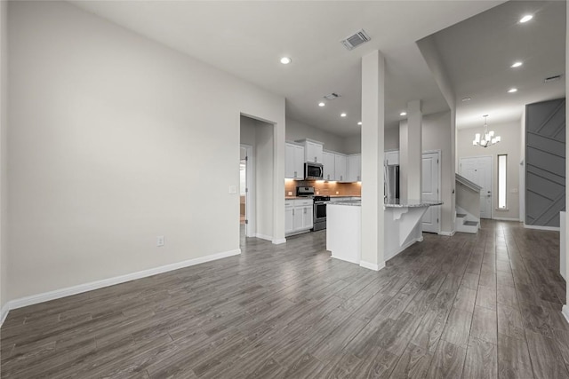 7808 Glover Dr, Austin, TX 78744 - unfurnished living room with dark wood-style flooring, a chandelier, recessed lighting, and stairs