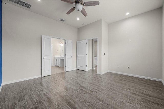 7808 Glover Dr, Austin, TX 78744 - unfurnished bedroom with wood finished floors, ensuite bath, recessed lighting, ceiling fan, and a high ceiling
