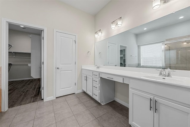 7808 Glover Dr, Austin, TX 78744 - full bathroom featuring double vanity, a spacious closet, a shower stall, and tile patterned floors