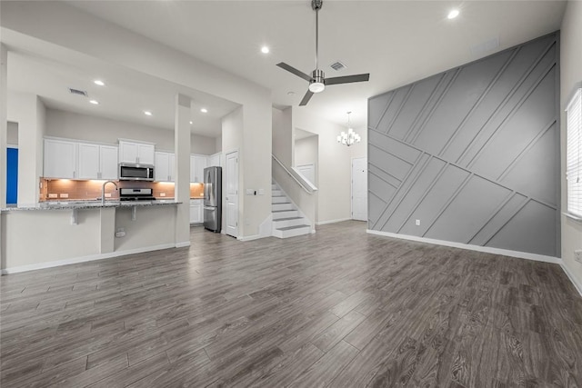 7808 Glover Dr, Austin, TX 78744 - unfurnished living room with dark wood-style flooring, a chandelier, stairs, ceiling fan, and recessed lighting