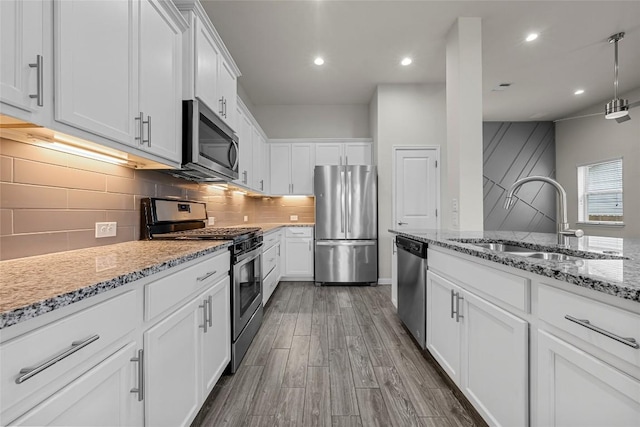 7808 Glover Dr, Austin, TX 78744 - kitchen featuring appliances with stainless steel finishes, white cabinetry, light stone counters, dark wood-style floors, and tasteful backsplash