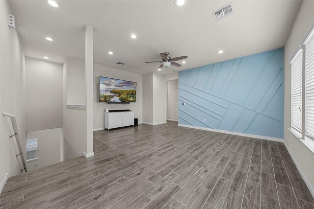 7808 Glover Dr, Austin, TX 78744 - unfurnished living room featuring wood finished floors, a ceiling fan, recessed lighting, and a decorative wall