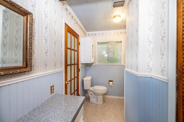 705 Dunning St, Gonzales, TX 78629 - bathroom with tile patterned flooring, wallpapered walls, vanity, and a wainscoted wall