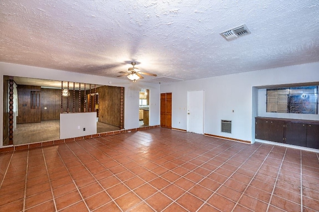 705 Dunning St, Gonzales, TX 78629 - unfurnished living room featuring ceiling fan, a textured ceiling, heating unit, and tile patterned flooring