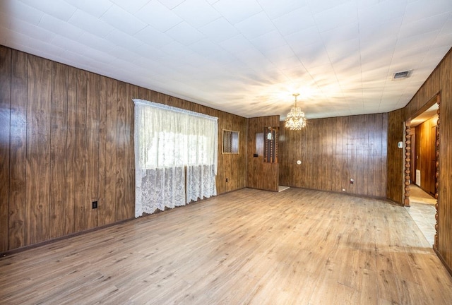 705 Dunning St, Gonzales, TX 78629 - unfurnished room with a chandelier, light wood-style floors, and wood walls