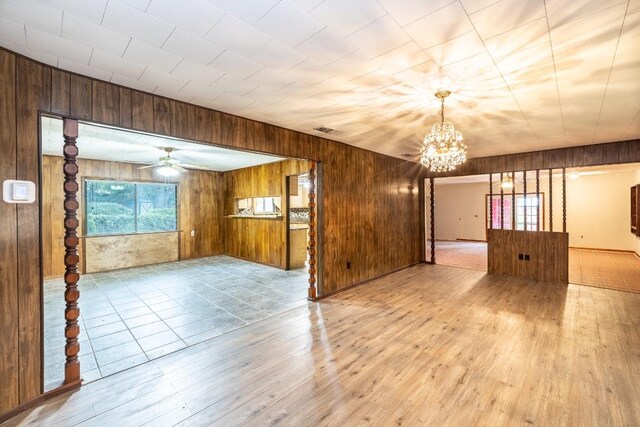 705 Dunning St, Gonzales, TX 78629 - unfurnished room with wood-type flooring, a chandelier, wood walls, and a ceiling fan