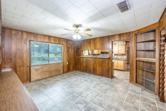 705 Dunning St, Gonzales, TX 78629 - kitchen with wooden walls, ceiling fan, a peninsula, and brown cabinetry
