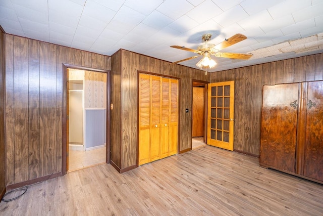 705 Dunning St, Gonzales, TX 78629 - unfurnished bedroom with a closet, wooden walls, wood finished floors, and a ceiling fan