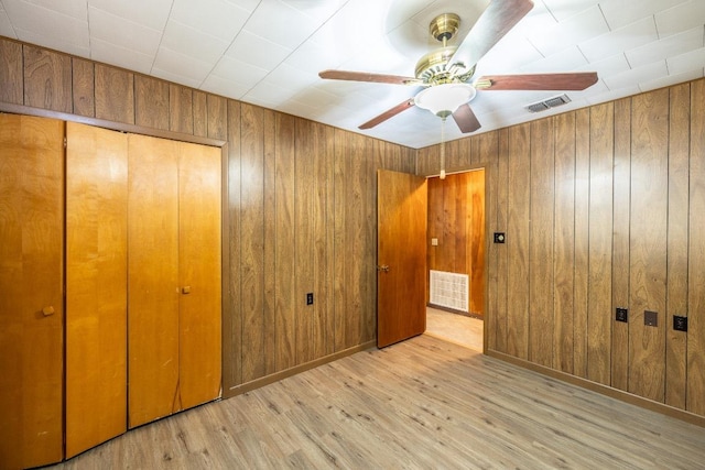 705 Dunning St, Gonzales, TX 78629 - unfurnished bedroom with a closet, wood finished floors, wooden walls, and ceiling fan