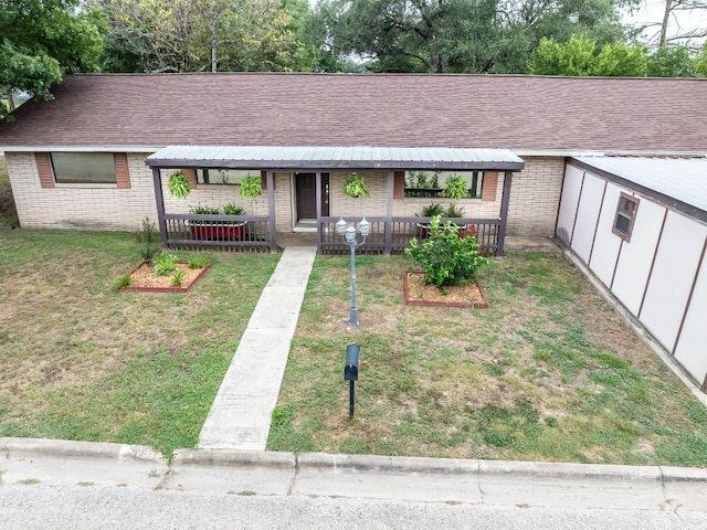 705 Dunning St, Gonzales, TX 78629 - single story home featuring brick siding, a porch, a front yard, and a shingled roof
