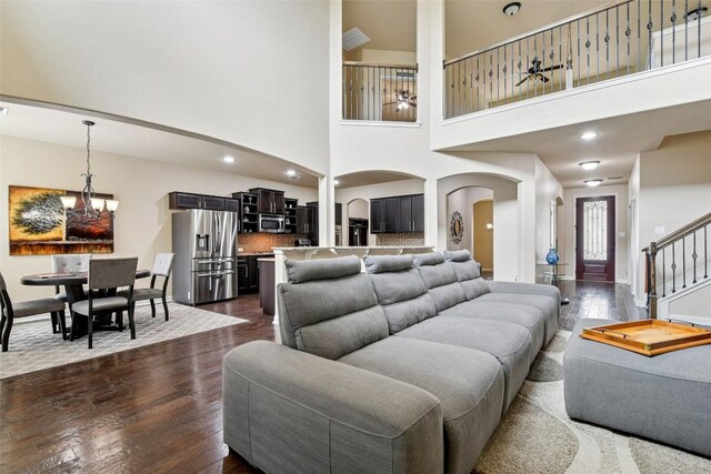 3713 Glastonbury Trl, Pflugerville, TX 78660 - living room with arched walkways, a chandelier, dark wood-style floors, a towering ceiling, and stairway
