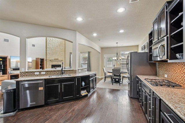 3713 Glastonbury Trl, Pflugerville, TX 78660 - kitchen featuring appliances with stainless steel finishes, open shelves, dark cabinetry, backsplash, and dark wood-type flooring