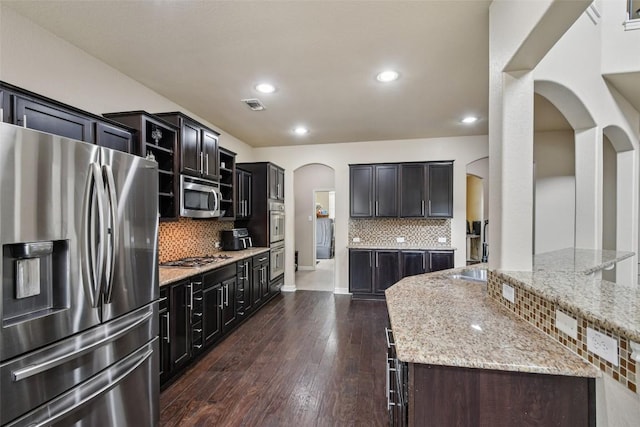 3713 Glastonbury Trl, Pflugerville, TX 78660 - kitchen with appliances with stainless steel finishes, arched walkways, decorative backsplash, light stone counters, and recessed lighting