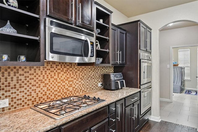 3713 Glastonbury Trl, Pflugerville, TX 78660 - kitchen featuring appliances with stainless steel finishes, open shelves, arched walkways, washer / clothes dryer, and dark brown cabinetry