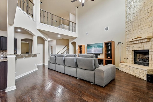 3713 Glastonbury Trl, Pflugerville, TX 78660 - living room featuring a ceiling fan, a stone fireplace, dark wood-style floors, stairs, and a high ceiling
