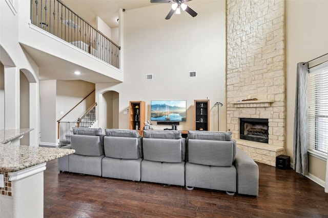 3713 Glastonbury Trl, Pflugerville, TX 78660 - living room featuring ceiling fan, a high ceiling, dark wood-style flooring, a fireplace, and stairs