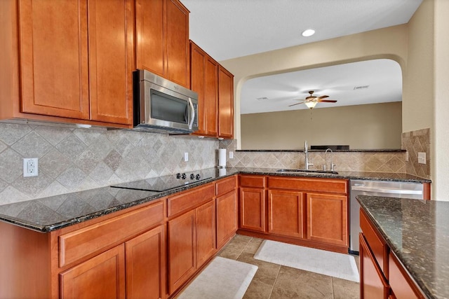 301 Wye Oak St, Austin, TX 78748 - kitchen with appliances with stainless steel finishes, a ceiling fan, arched walkways, backsplash, and brown cabinetry