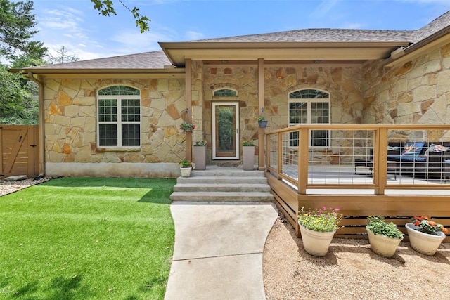 267 Corral Rd, Smithville, TX 78957 - view of exterior entry with stone siding, a yard, and a shingled roof
