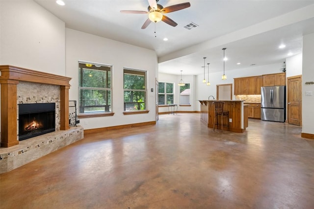 267 Corral Rd, Smithville, TX 78957 - unfurnished living room featuring finished concrete floors, ceiling fan, recessed lighting, and a lit fireplace