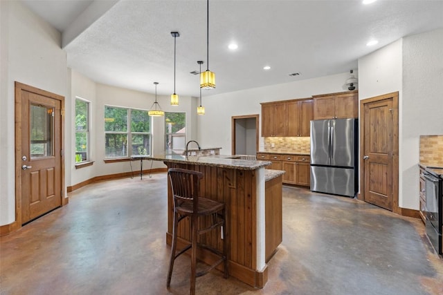 267 Corral Rd, Smithville, TX 78957 - kitchen with freestanding refrigerator, finished concrete floors, decorative backsplash, recessed lighting, and a kitchen bar