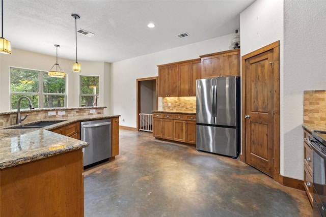 267 Corral Rd, Smithville, TX 78957 - kitchen featuring appliances with stainless steel finishes, backsplash, finished concrete flooring, brown cabinetry, and stone countertops