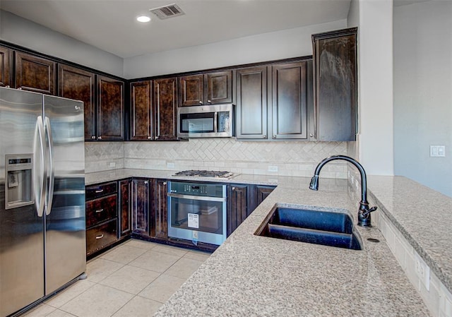 2836 Garnet Ridge Dr, Leander, TX 78641 - kitchen featuring stainless steel appliances, decorative backsplash, dark brown cabinetry, light stone counters, and recessed lighting