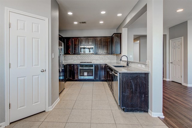 2836 Garnet Ridge Dr, Leander, TX 78641 - kitchen with stainless steel appliances, light stone countertops, tasteful backsplash, dark brown cabinetry, and recessed lighting