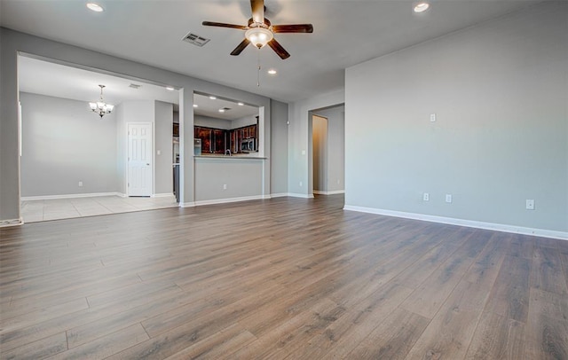 2836 Garnet Ridge Dr, Leander, TX 78641 - unfurnished living room featuring a ceiling fan, a chandelier, wood finished floors, and recessed lighting
