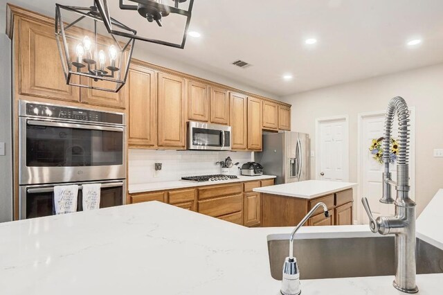 19709 Vilamoura St, Pflugerville, TX 78660 - kitchen featuring appliances with stainless steel finishes, light countertops, backsplash, a kitchen island, and a chandelier