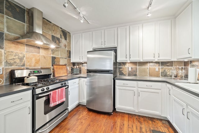 1807 Cullen Ave, Austin, TX 78757 - kitchen with stainless steel appliances, rail lighting, wall chimney range hood, white cabinetry, and decorative backsplash