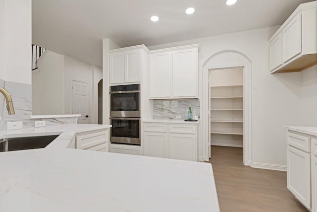 811 Zappa Dr, Cedar Park, TX 78613 - kitchen with stainless steel double oven, tasteful backsplash, light wood-style flooring, white cabinetry, and recessed lighting