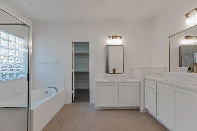 811 Zappa Dr, Cedar Park, TX 78613 - bathroom featuring two vanities, a bath, a shower stall, and a walk in closet