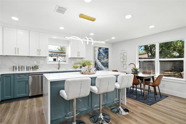 2400 Burly Oak Dr, Austin, TX 78745 - kitchen featuring dishwasher, light countertops, a kitchen breakfast bar, a center island, and light wood-style floors